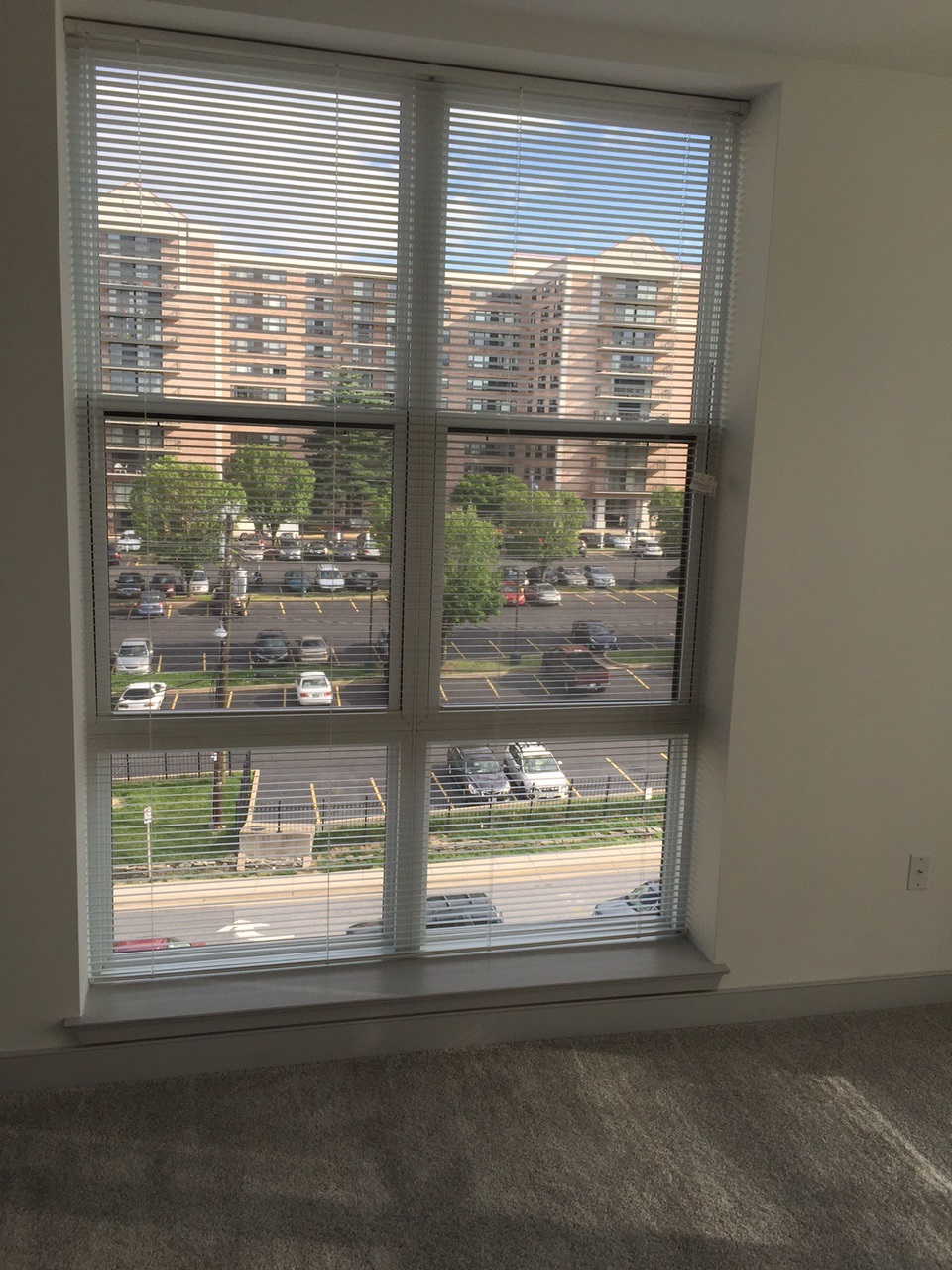 interior view looking out of window, scene outside shows a carpark in front of a large building