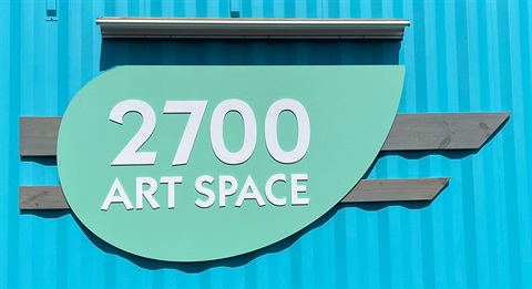 2700 Art Space retro inspired teal and green sign on a bright blue shipping container.