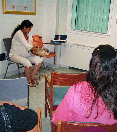 WIC breastfeeding educator demonstrates infant feeding techniques with a baby doll during a class.