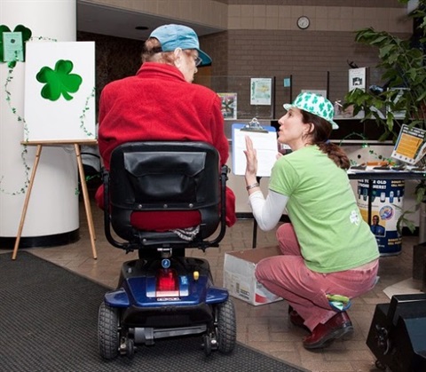 Person in electric chair listening to a person with a clipboard