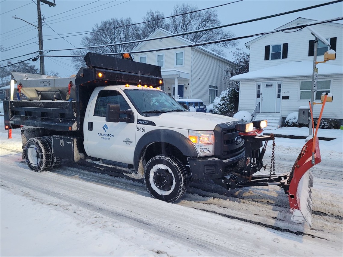 snowplow truck driving on snowy residential area