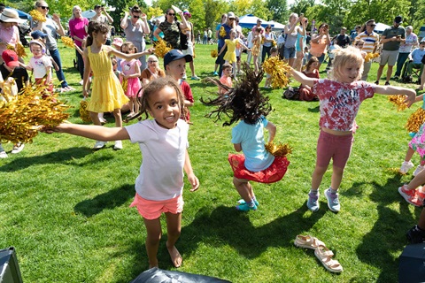 group of kids jumping and dancing outdoors at a park