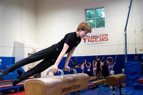 boy performing gymnastics on a beam