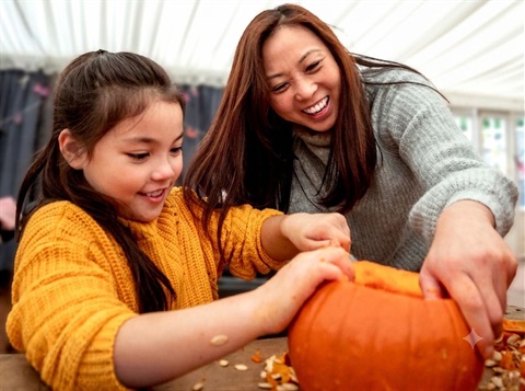 mom and daughter carving pumpkin.
