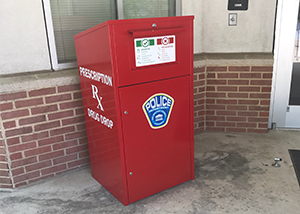 Red box with police patch and text reading prescription drug drop