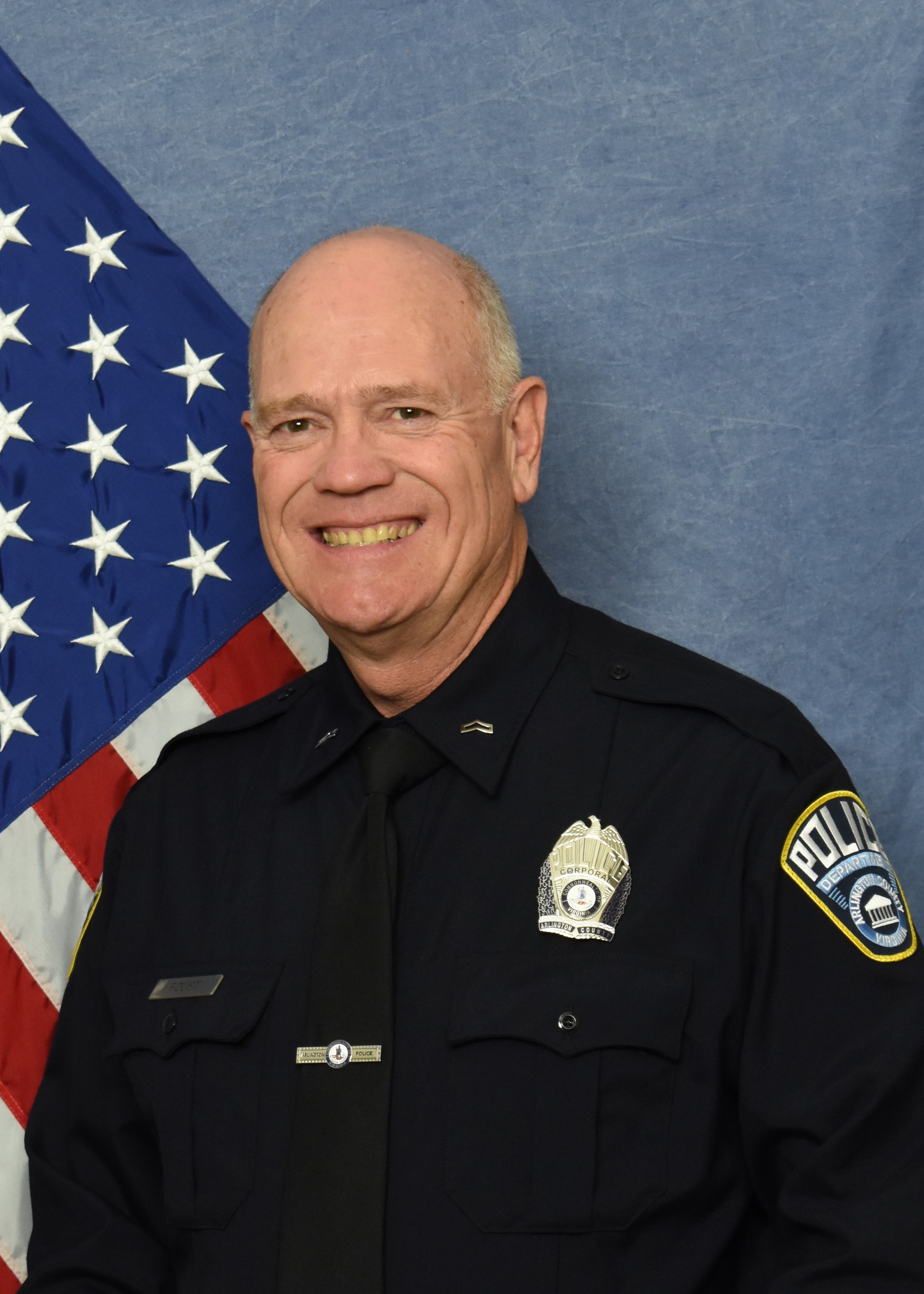 Official police photograph of Corporal Barry Foust in front of a blue background with American flag