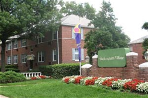 Buckingham apartments. A red brick building with greenery and flowers in front of the property signage.