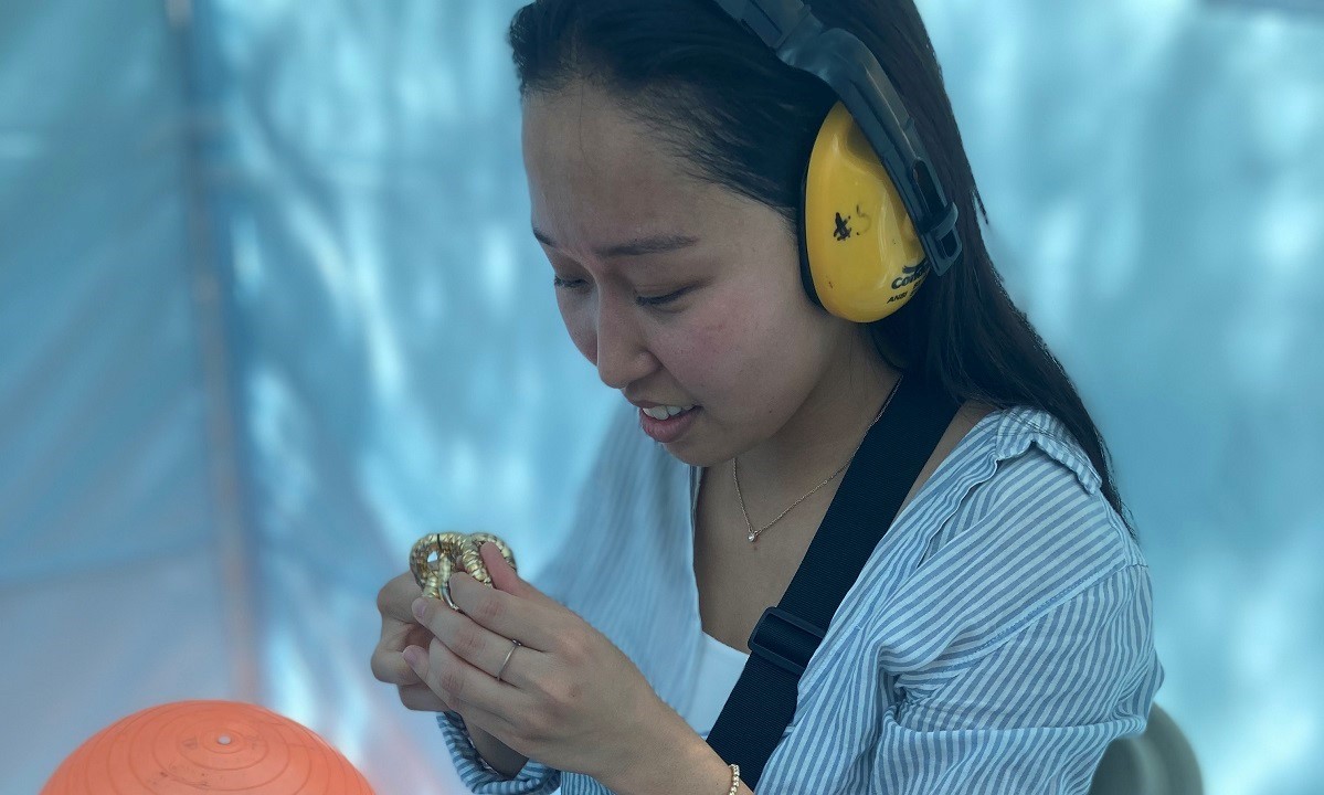 Woman wearing noise cancelling headphones sitting in the sensory tent using a figdet